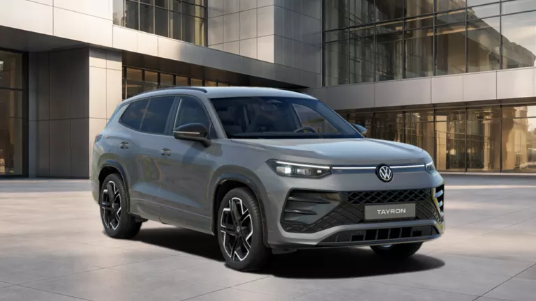 VW Tayron R-Line eHybrid in grauer Lackierung vor moderner Glasfassade
