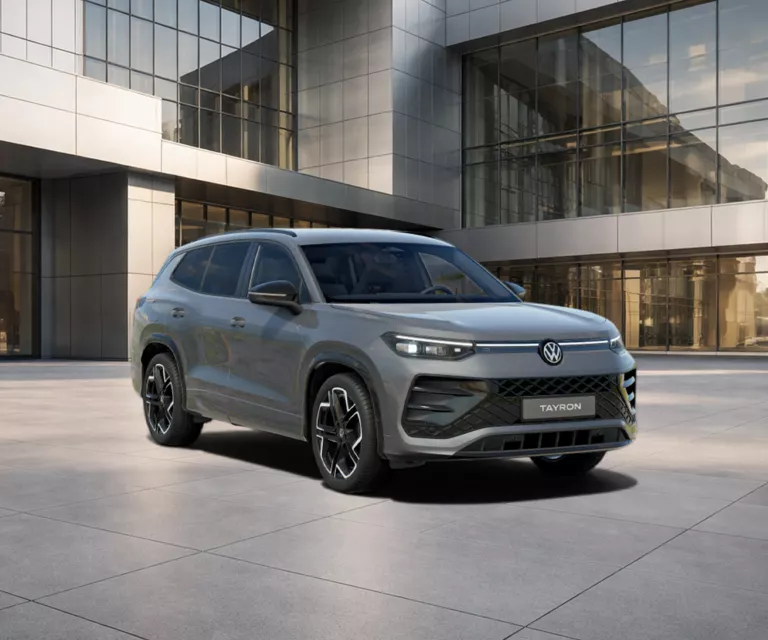 VW Tayron R-Line eHybrid in grauer Lackierung vor moderner Glasfassade