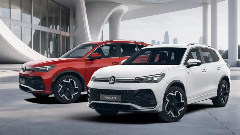 Zwei VW Tiguan R-Line SUV nebeneinander vor modernem Gebäude, einer weiß, einer rot 