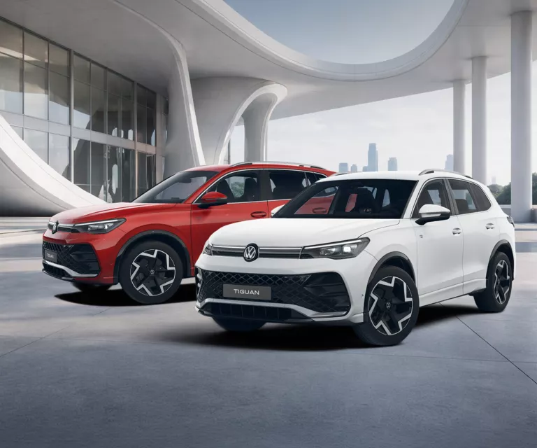 Zwei VW Tiguan R-Line SUV nebeneinander vor modernem Gebäude, einer weiß, einer rot 