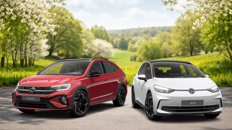 Frühlingshafte Landschaft mit blühenden Bäumen und grüner Wiese im Hintergrund, davor VW Taigo in Rot und ID.3 in Weiß.