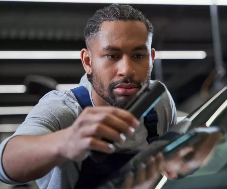 VW-Servicemitarbeiter untersucht eine Windschutzscheibe nach Schäden – Glasreparatur Service  