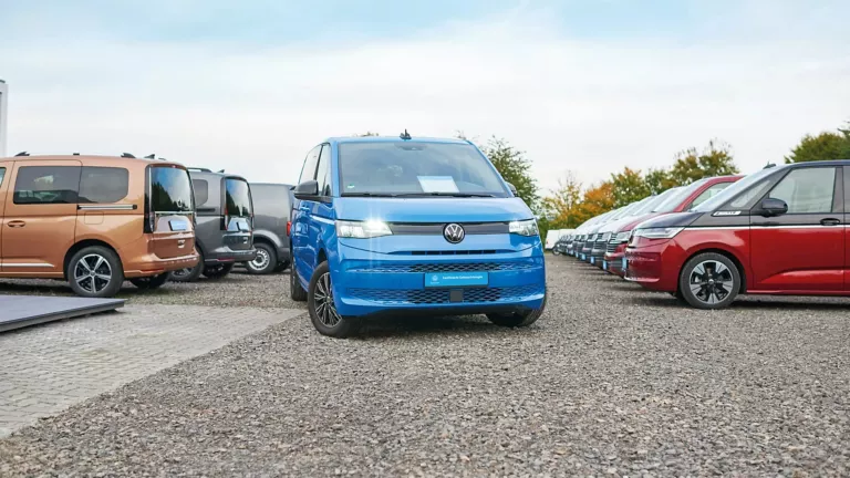 Blauer Volkswagen ID. Buzz Elektro-Van steht auf einem Parkplatz mit weiteren Fahrzeugen im Hintergrund