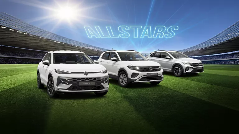 Drei VW Modelle stehen in der Mitte eines vollbesetzten Fußballstadions.