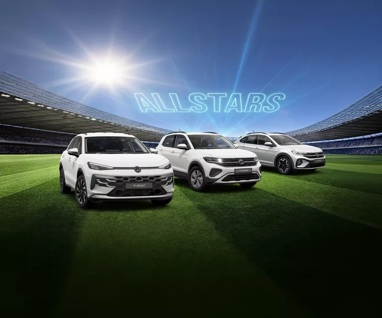 Drei VW Modelle stehen in der Mitte eines vollbesetzten Fußballstadions.