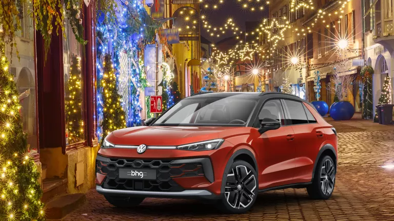 Ein gelber VW T-Roc R-Line und ein roter VW T-Roc Style stehen nebeneinander vor einem modernen Gebäude.