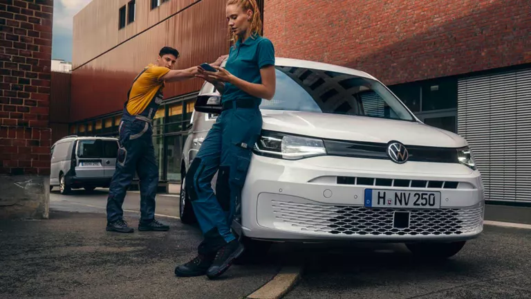 Zwei Handwerker lehnen sich an einen VW Caddy Cargo.