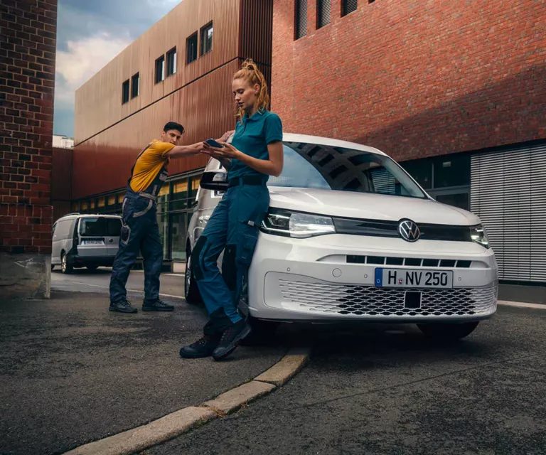Zwei Handwerker lehnen sich an einen VW Caddy Cargo.