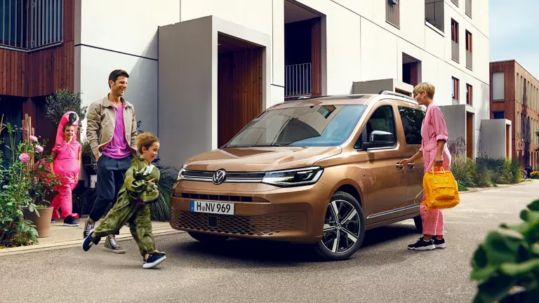 Familie steht um einen VW Caddy.