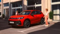 Una Volkswagen rossa con di fianco due persone