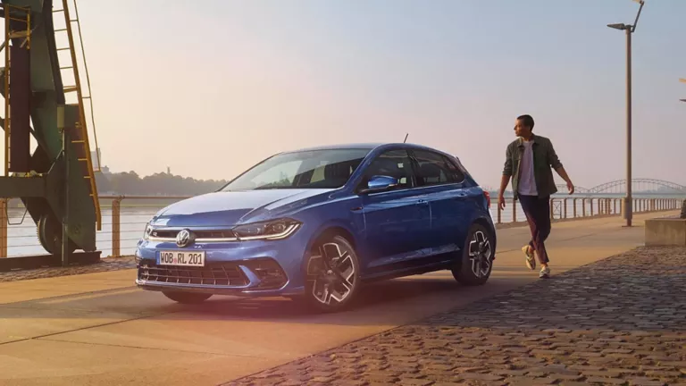 Un hombre en la parte de atrás de un Volkswagen Polo aparcado junto al río