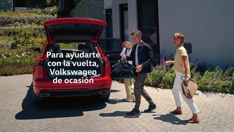 Una familia acercándose a un Volkswagen rojo