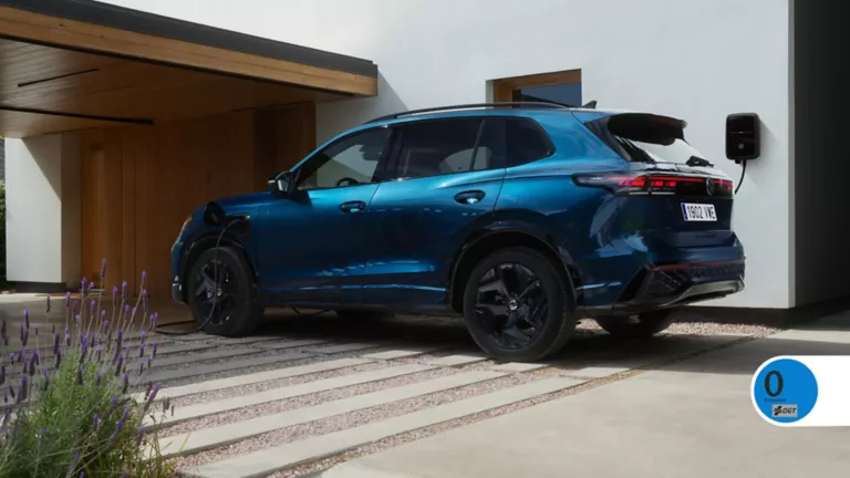 Un Tiguan híbrido azul cargando en la entrada de una casa