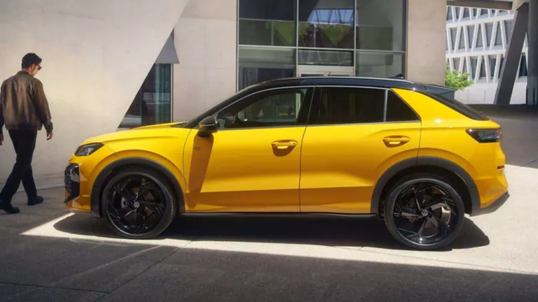 Un hombre pasando por delante de un Volkswagen T-Roc amarillo aparcado junto un edificio