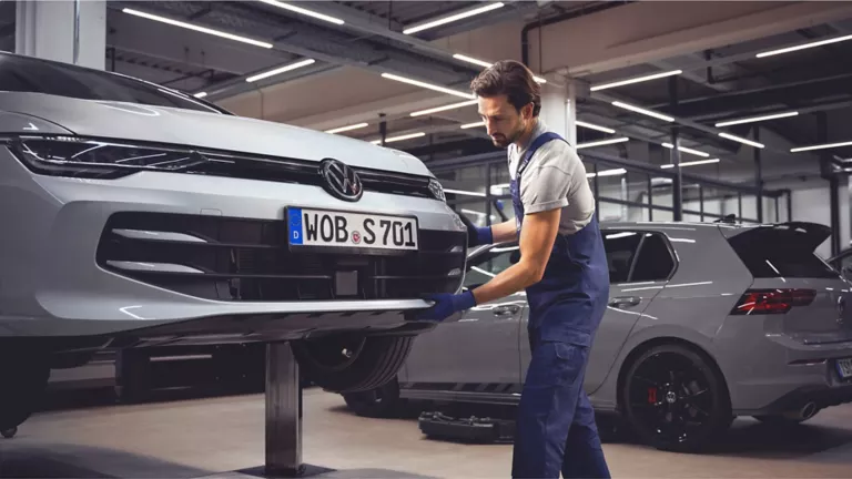 Un mecánico y un cliente revisando la parte baja de un Volkswagen