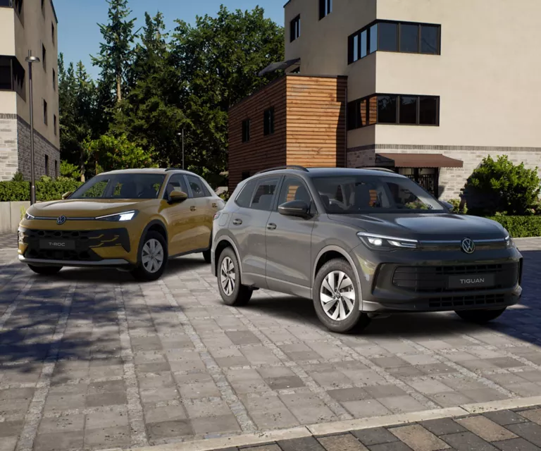 VW T-Roc und VW Tiguan stehen vor eienr Hausfront.