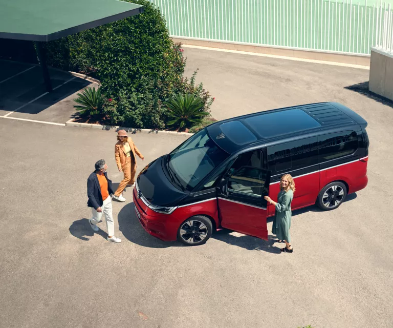 Drei Menschne um einen VW Multivan.