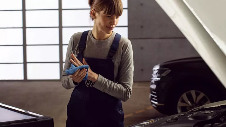 Una agente de servicio revisando el motor de un Volkswagen