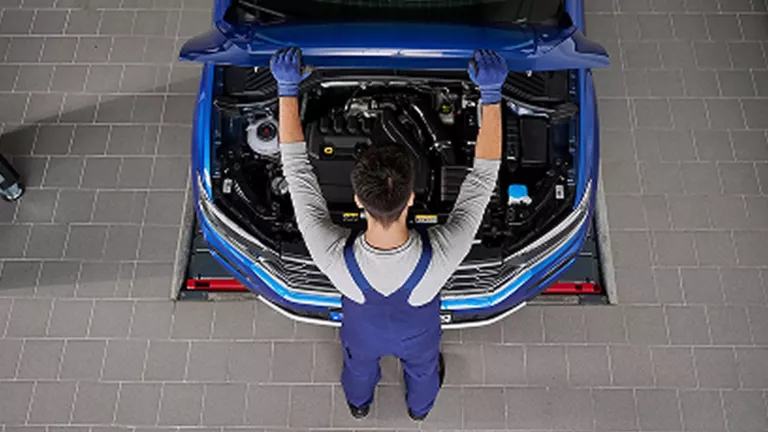 Una niña sentada dentro de un Volkswagen hablando con su madre asomada a la ventanilla