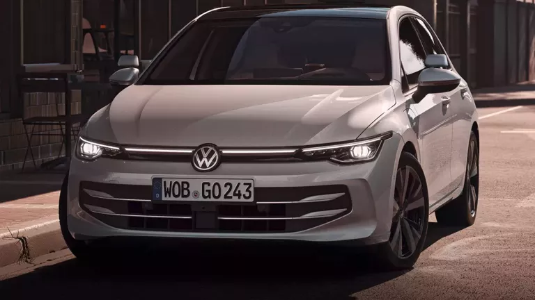 Ein weißer VW als Fahrschulauto umgebaut parkt vor einem Cafe.