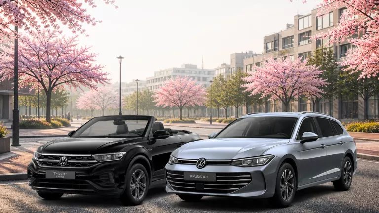 VW T-Roc Cabriolet und Passat Business auf einen Parkplatz mit blühenden Bäumen.
