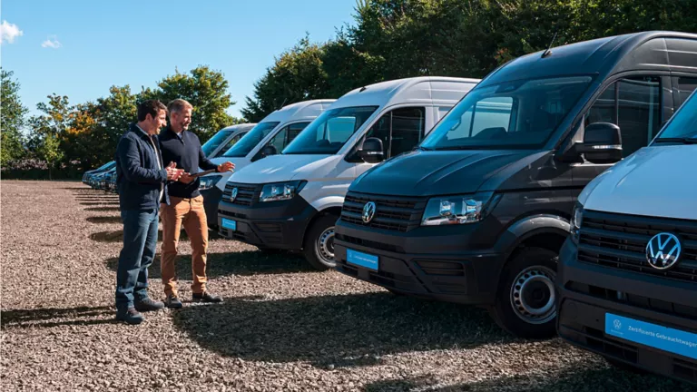 Zwei Männer sehen sich einen VW Crafter auf einem Autohof an.