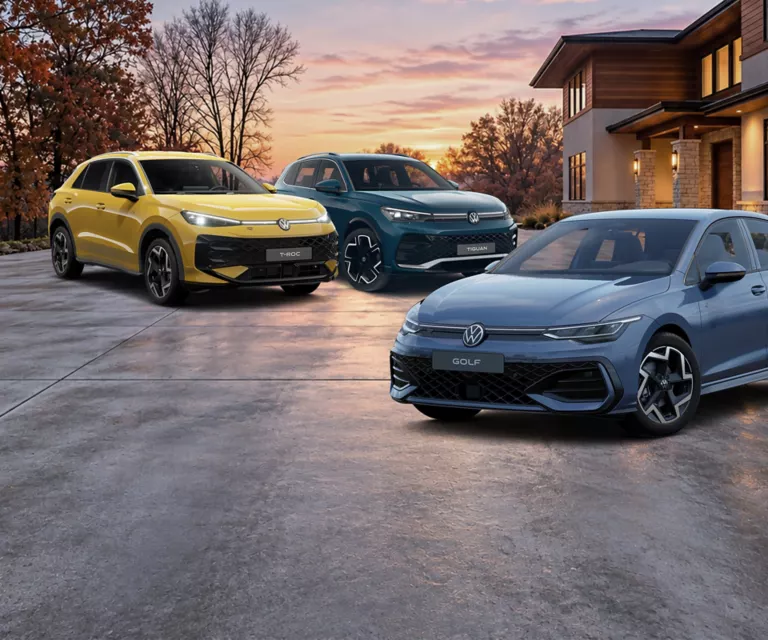 VW T-Roc, VW Tiguan und ein VW Golf parken nebeneinander in großen Hauseinfahrt.