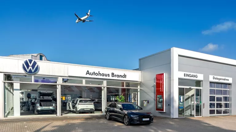 Ein Flugzeug fliegt über das Autohaus von Brandt