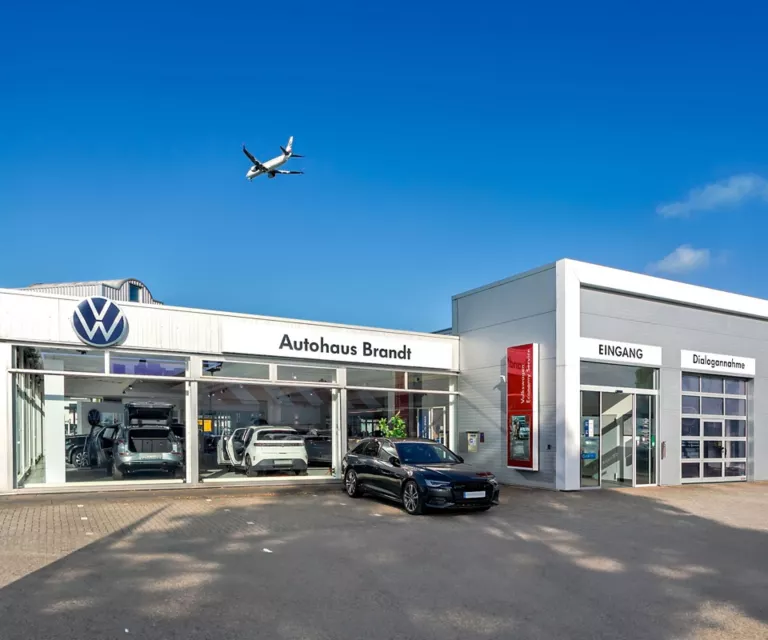 Ein Flugzeug fliegt über das Autohaus von Brandt