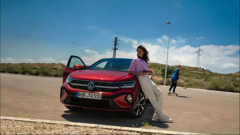 Una chica apoyada en Volkswagen Taigo rojo visto de frente en un parking