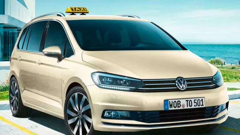 Ein VW Touran als Taxi umbau parkt vor einem modernen Gebäude.