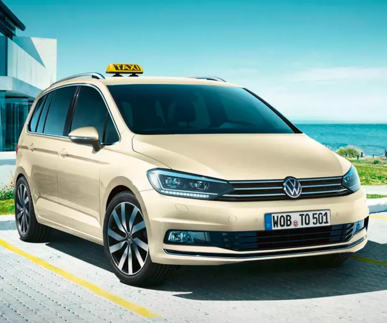 Ein VW Touran als Taxi umbau parkt vor einem modernen Gebäude.