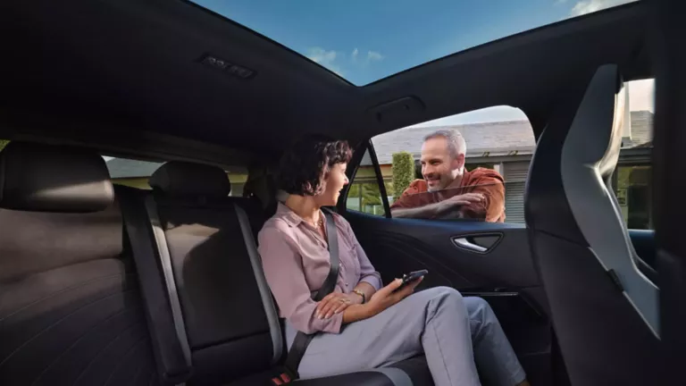 Una mujer sentada dentro de un Volkswagen hablando con un hombre en el exterior