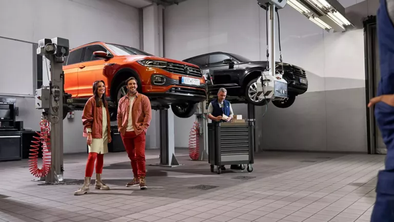 Dos persona en un taller Volkswagen y unos coches en plataformas elevadoras