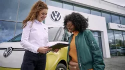 Un addetta Service e una cliente consultano un tablet. Sullo sfondo ID. Buzz e una concessionaria service VW.