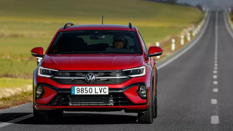 Un Volkswagen Taigo rojo visto de frente circulando por una larga carretera