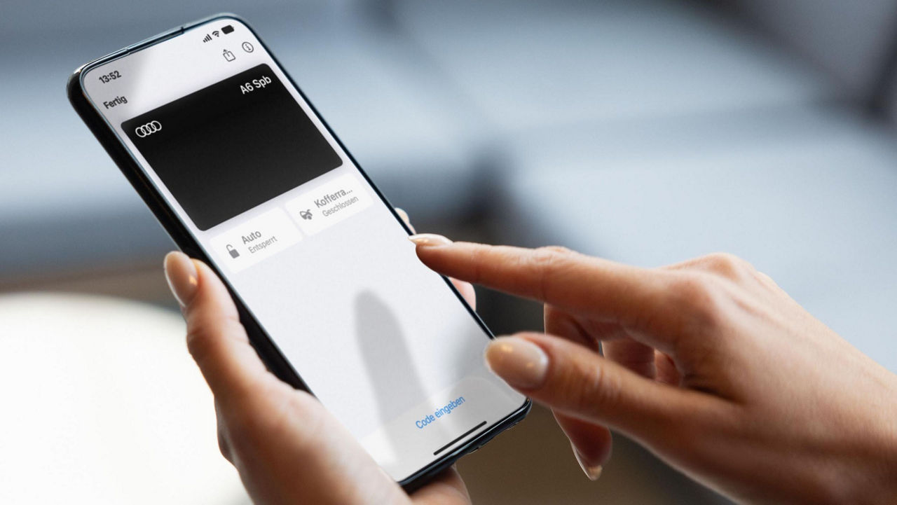 Close-up of a person using a smartphone app to manage Audi vehicle functions, including fuel status and remote control features, highlighting digital car key technology.