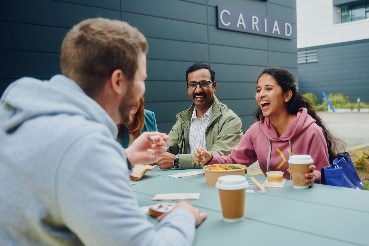 Colleagues sitting together outdoors at the workplace, reflecting a supportive culture and everyday benefits at CARIAD.