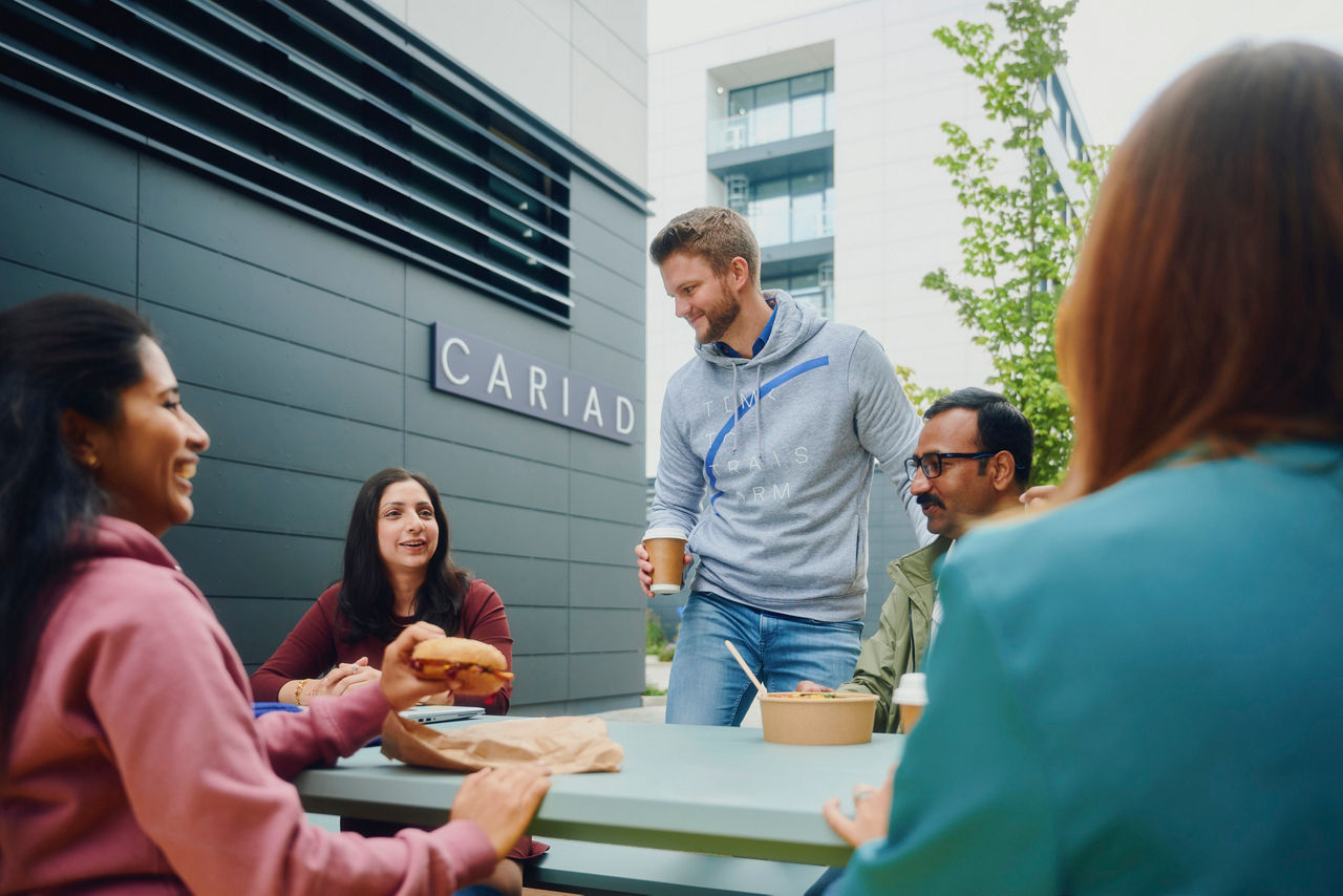 Group of colleagues having a casual outdoor lunch at a company campus.