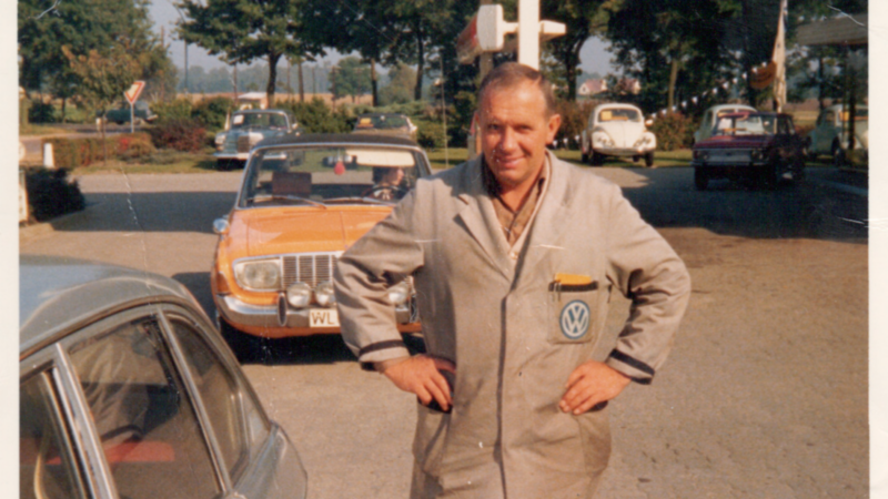 VW Mitarbeiter posiert vor einem Volkswagen 1970