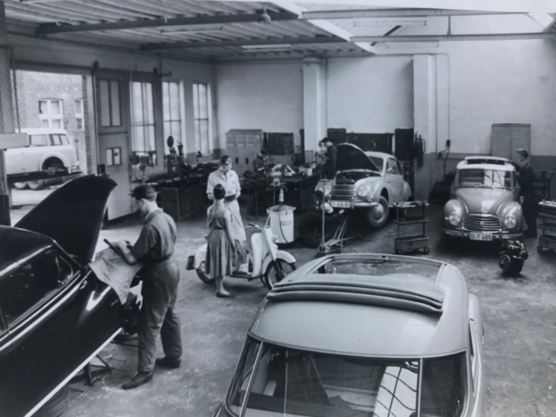 Volkswagen Autowerkstatt, in der verschiedene VW Oldtimern stehen, in Schwarz-Weiß