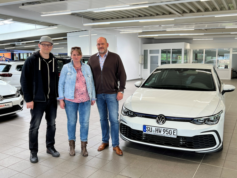 Drei Personen stehen vor weißem VW Golf GTE