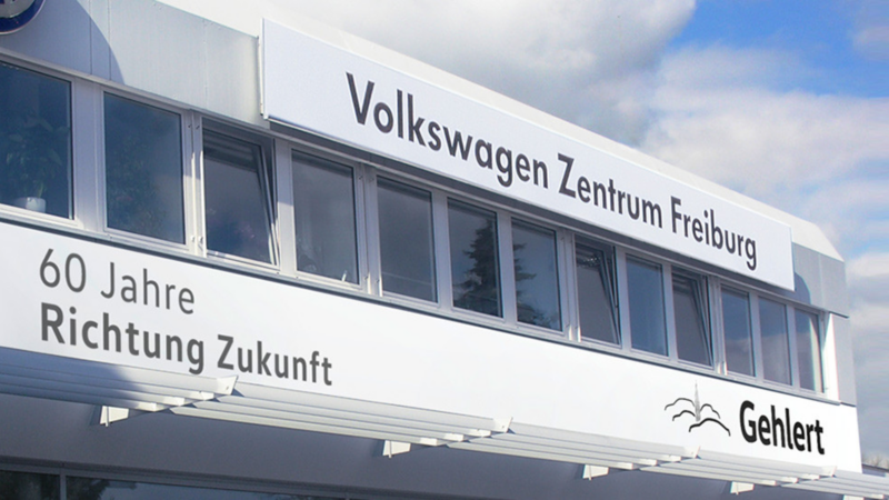 Fassade des Volkswagen Zentrums Freiburg mit Schriftzug '60 Jahre Richtung Zukunft' und Logo von Gehlert