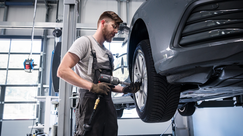 Mann befestigt Reifen an einen Volkswagen