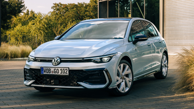 Silberner VW Golf auf einem Parkplatz vor einem modernen Gebäude.