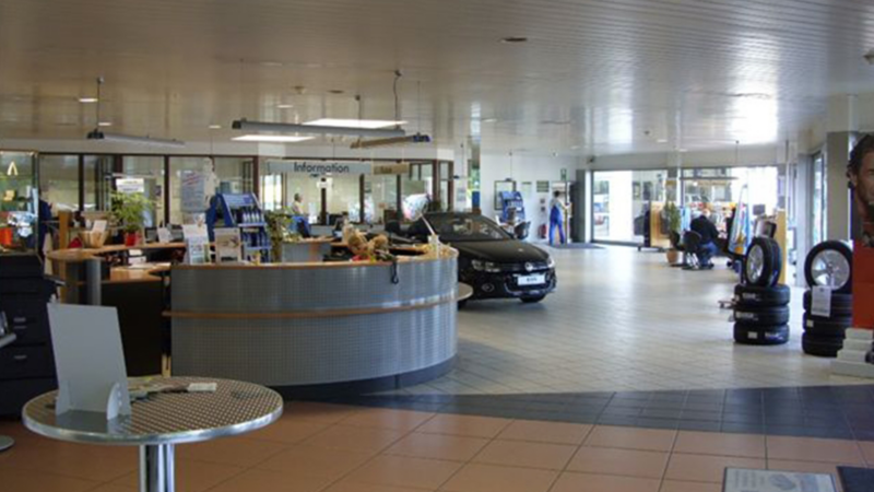 Autohaus von innen mit Empfang und geparkten Autos