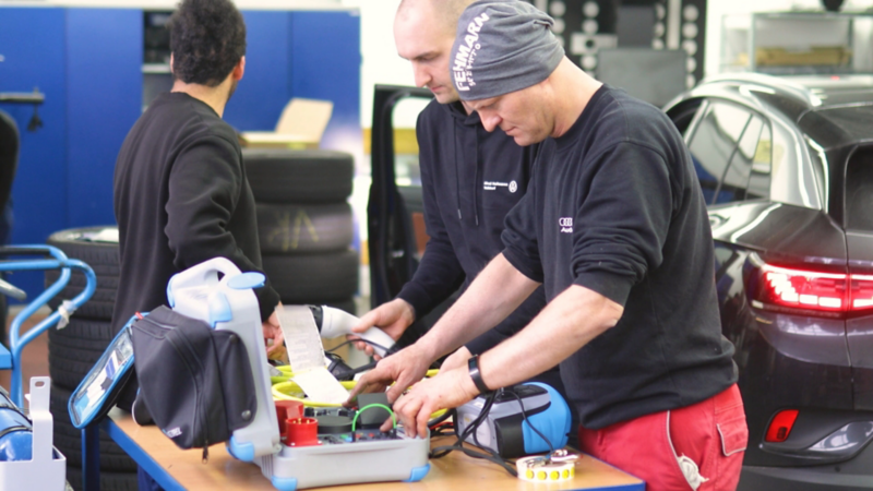 Männer in Arbeitskleidung hantieren in der Werkstatt