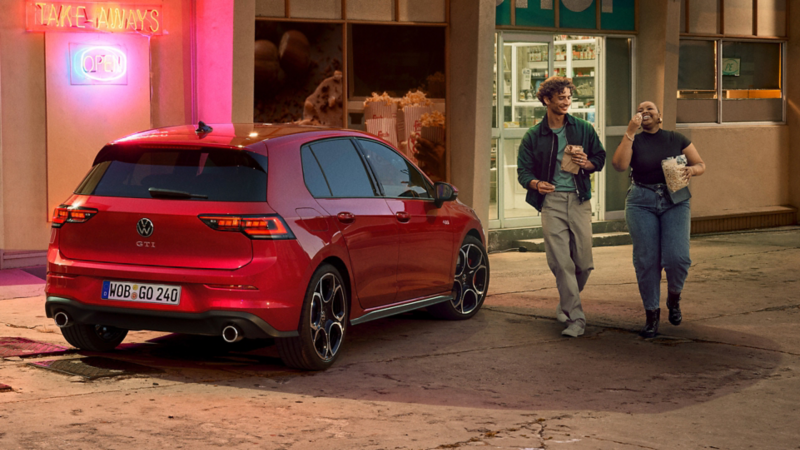 Rückansicht eines roten VW Golf GTI, der vor einem Gebäude steht.