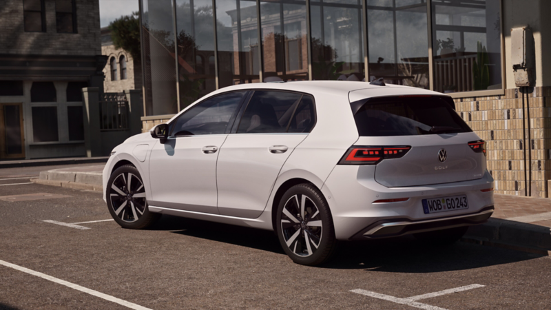 Seitliche Rückansicht eines weißen Golf, der vor einem Restaurant parkt.