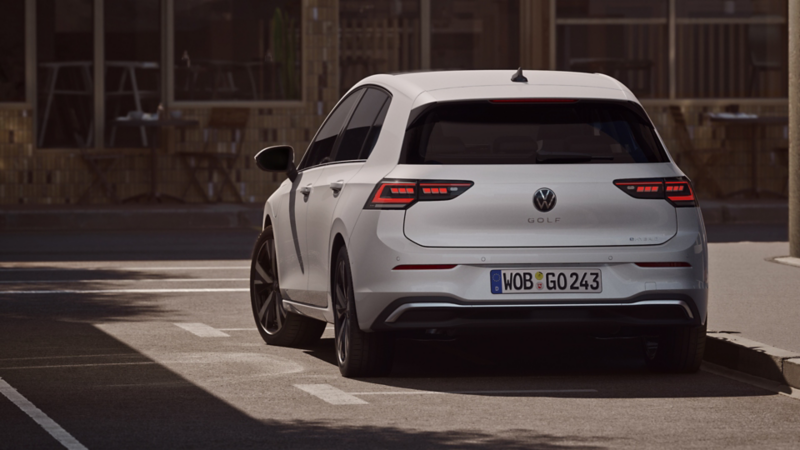 Blick auf das Heck eines am Straßenrand parkenden, weißen VW Golf.